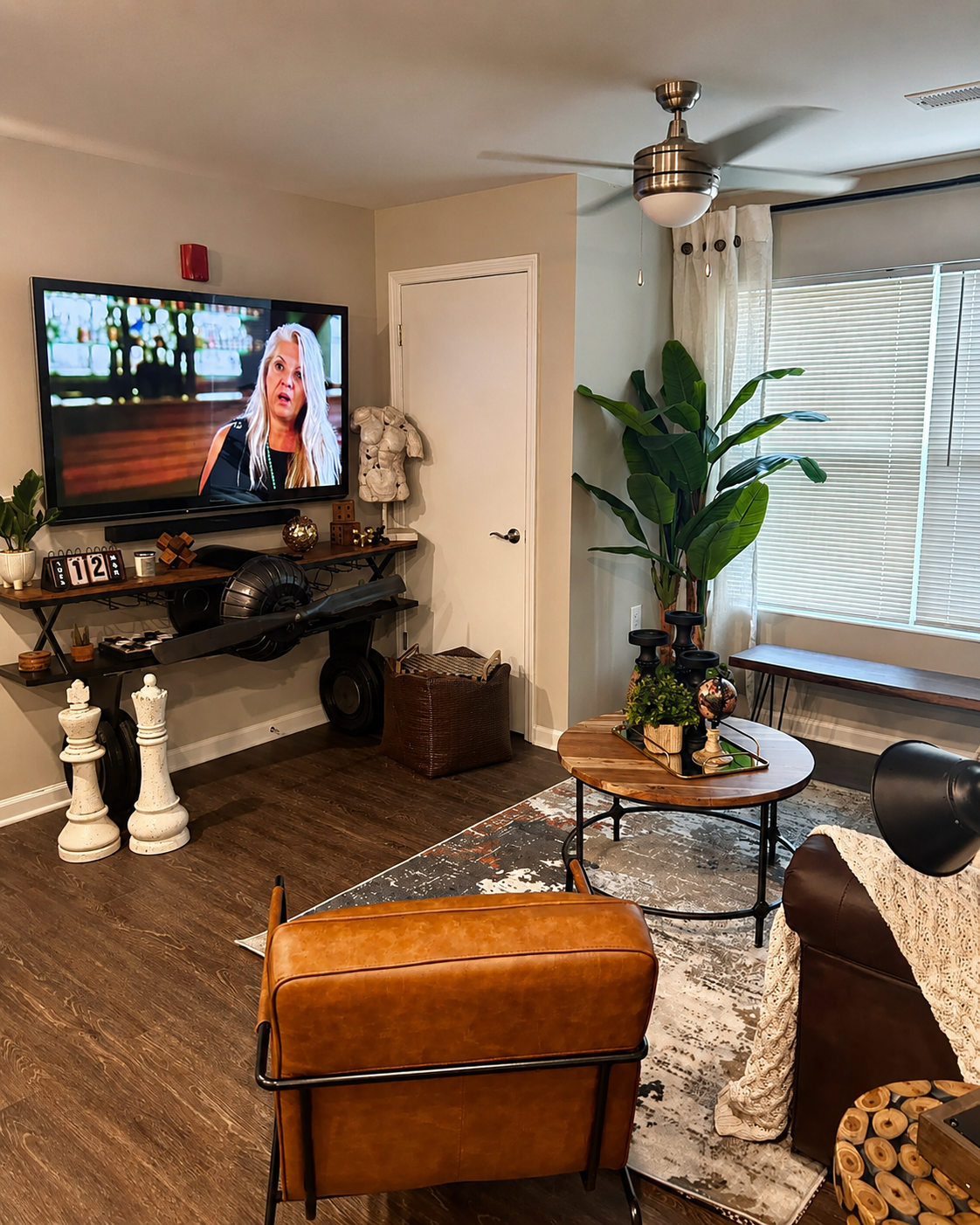 Apartment living room with leather sofa, industrial propeller console, and oversized chess piece decor