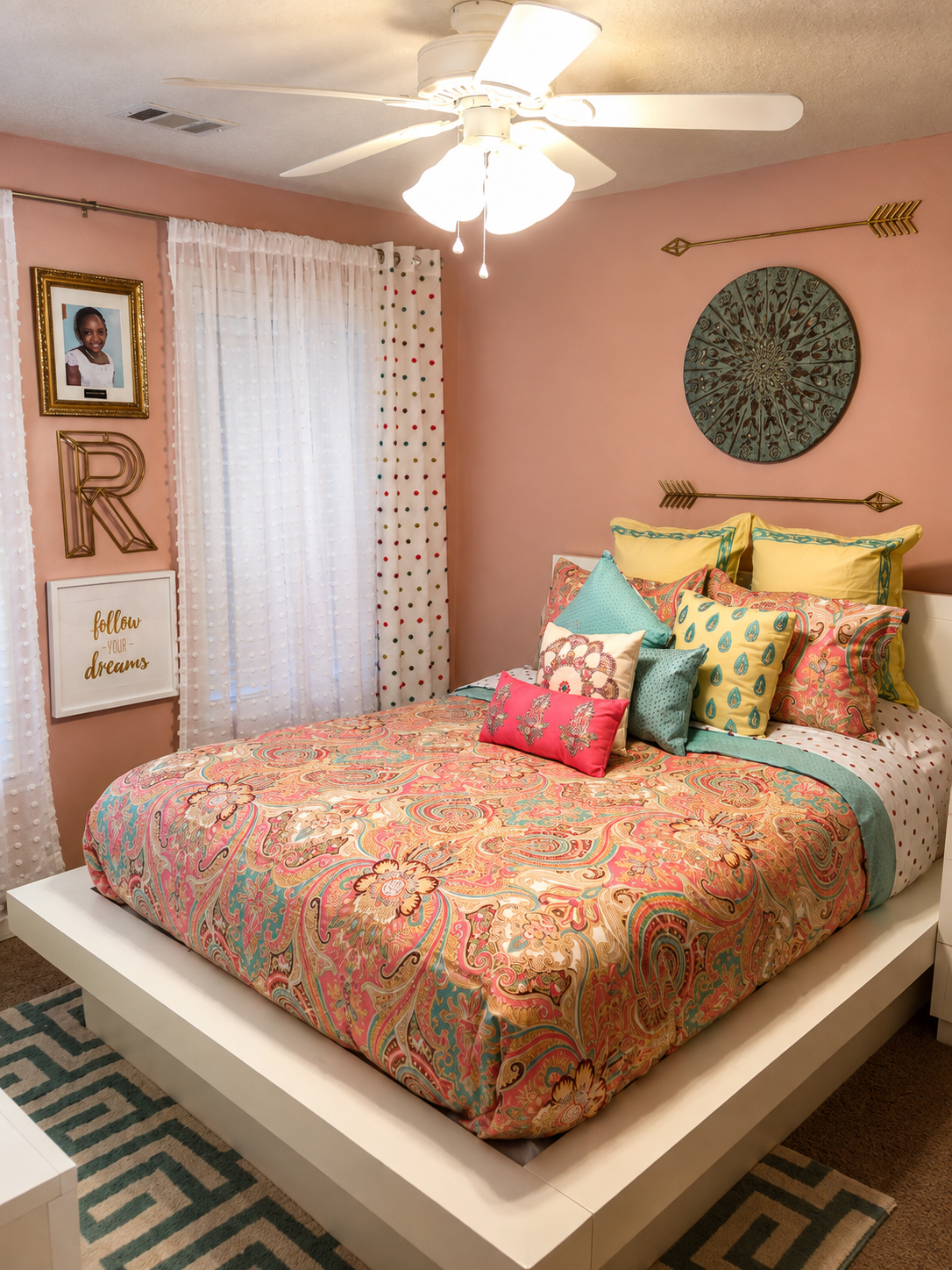 Girl's pink bedroom with paisley bedding, gold arrow wall decor, teal mandala hanging, and gallery wall