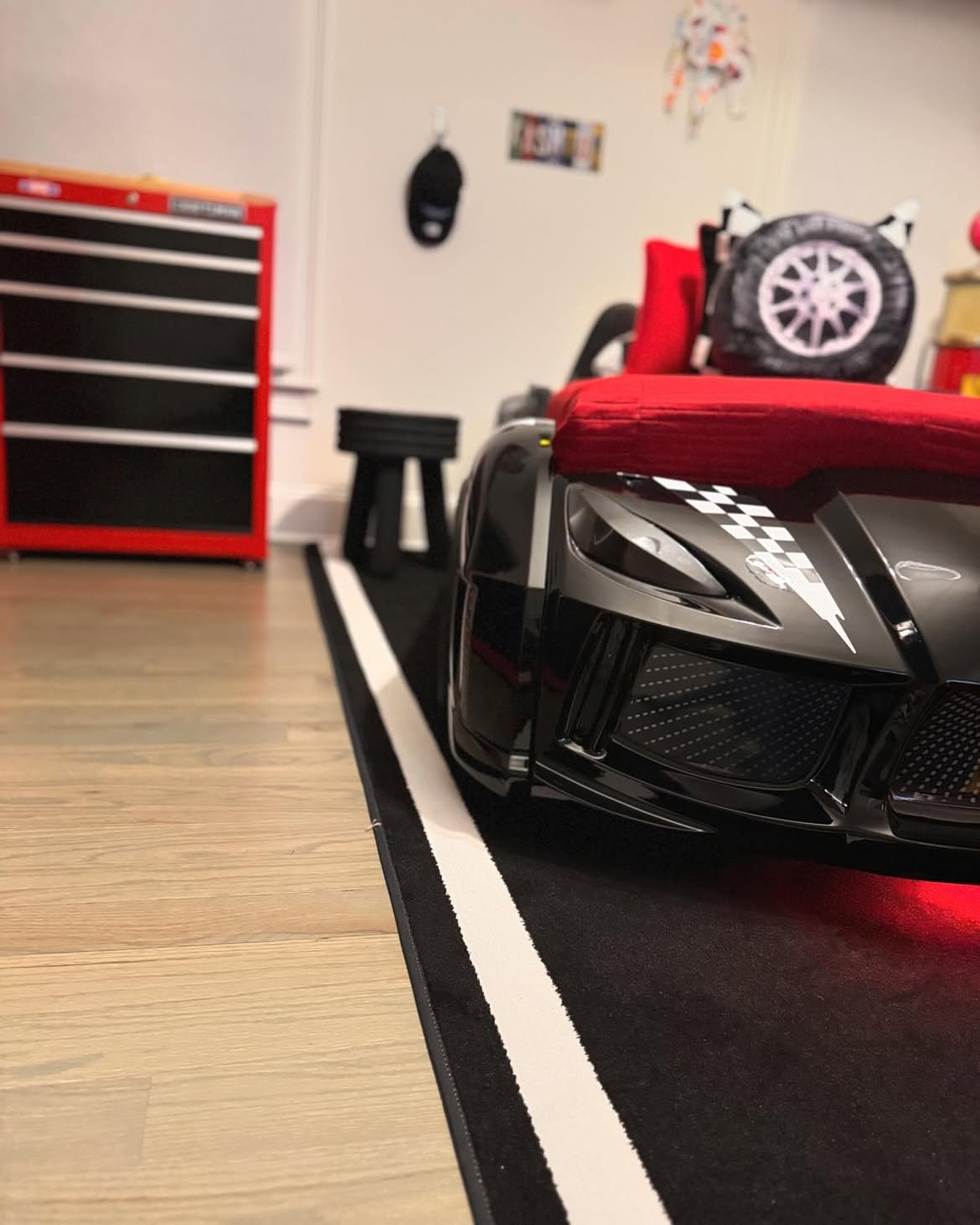 Race car themed bedroom with Corvette bed, checkered flags, traffic light, and Craftsman tool chest console