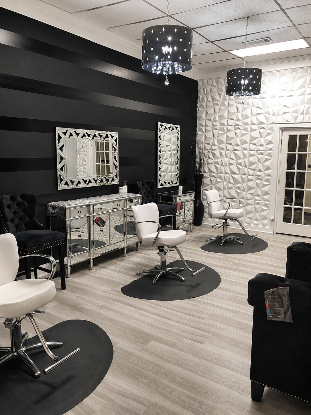 Noir & Mirror salon with black striped walls, white styling chairs, and crystal chandeliers