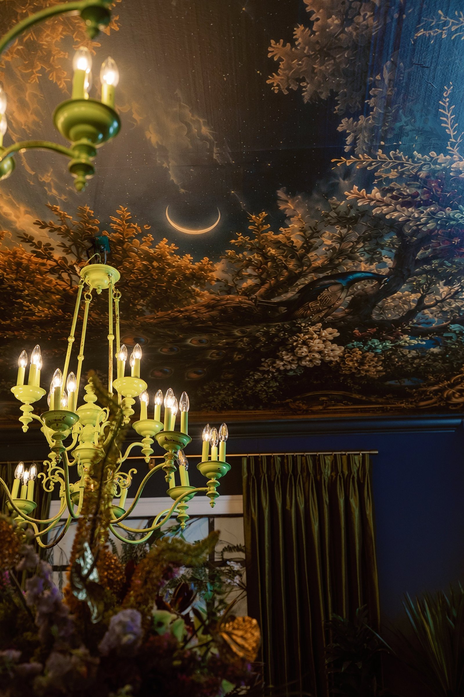 Hand-painted ceiling mural of a dark forest at night with a crescent moon and peacock perched in branches